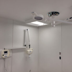 Surgical light fixture attached to wall with adjustable arms with air vent in a medical room with white walls
